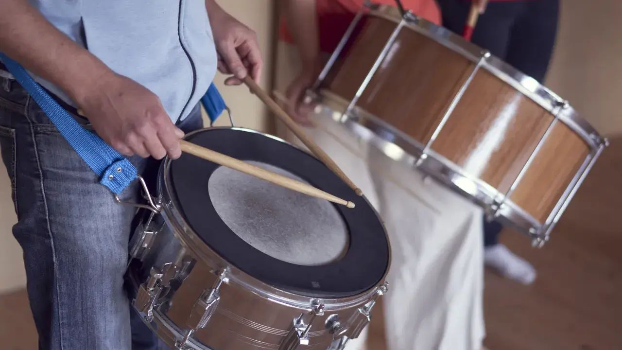 Des musiciens jouent de la percussion brésilienne, leurs mains tenant des baguettes prêtes à frapper les tambours.