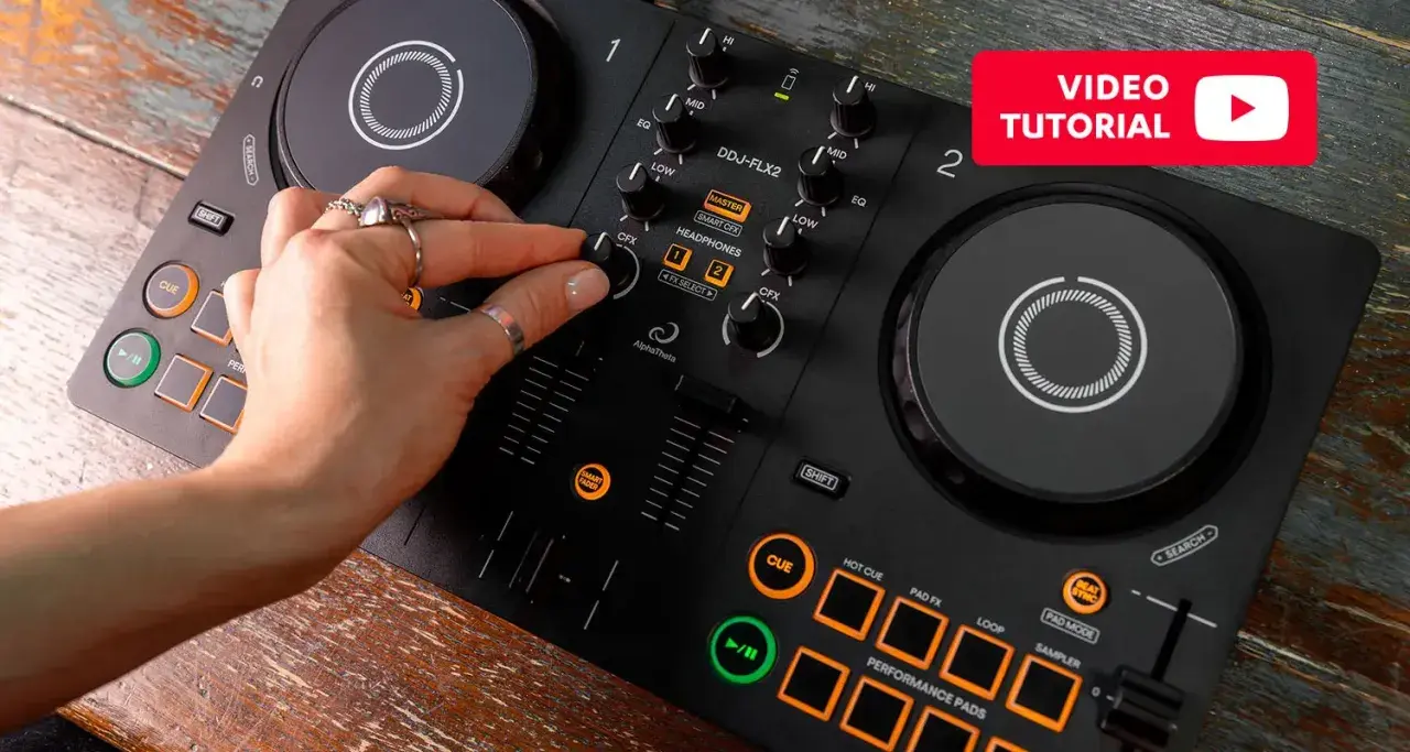 Main d'une personne manipulant une table de mixage pour créer sa propre musique électro. Tutoriel vidéo disponible.