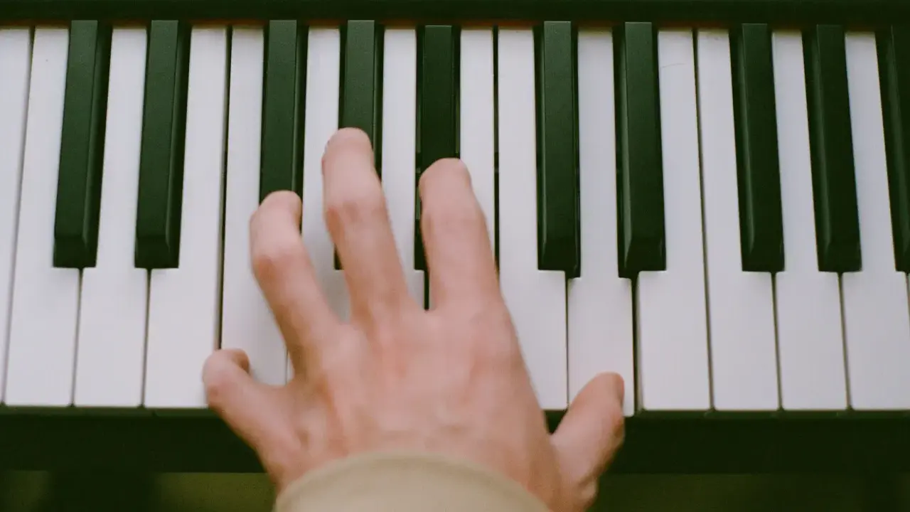 Main d'un pianiste sur des touches noires et blanches, symbolisant le passage de l'analogique au numérique.