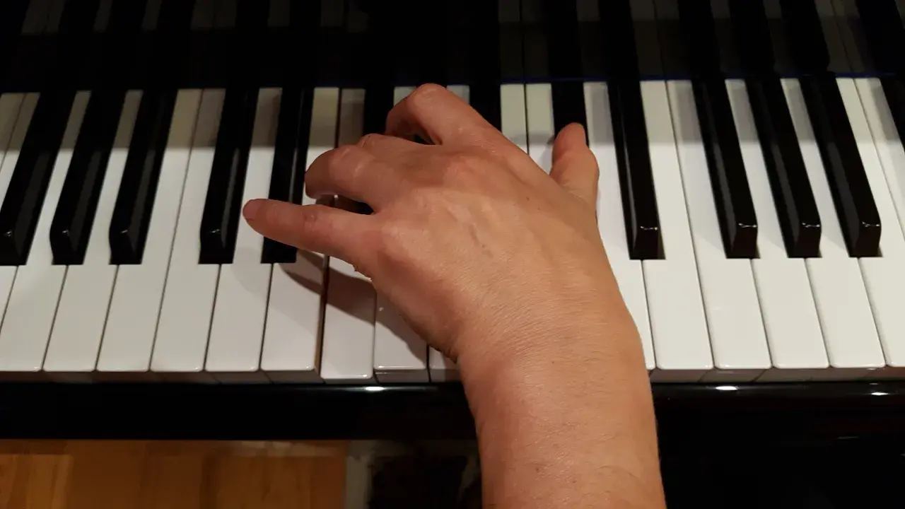 Main droite jouant un accord de ré mineur sur un piano.