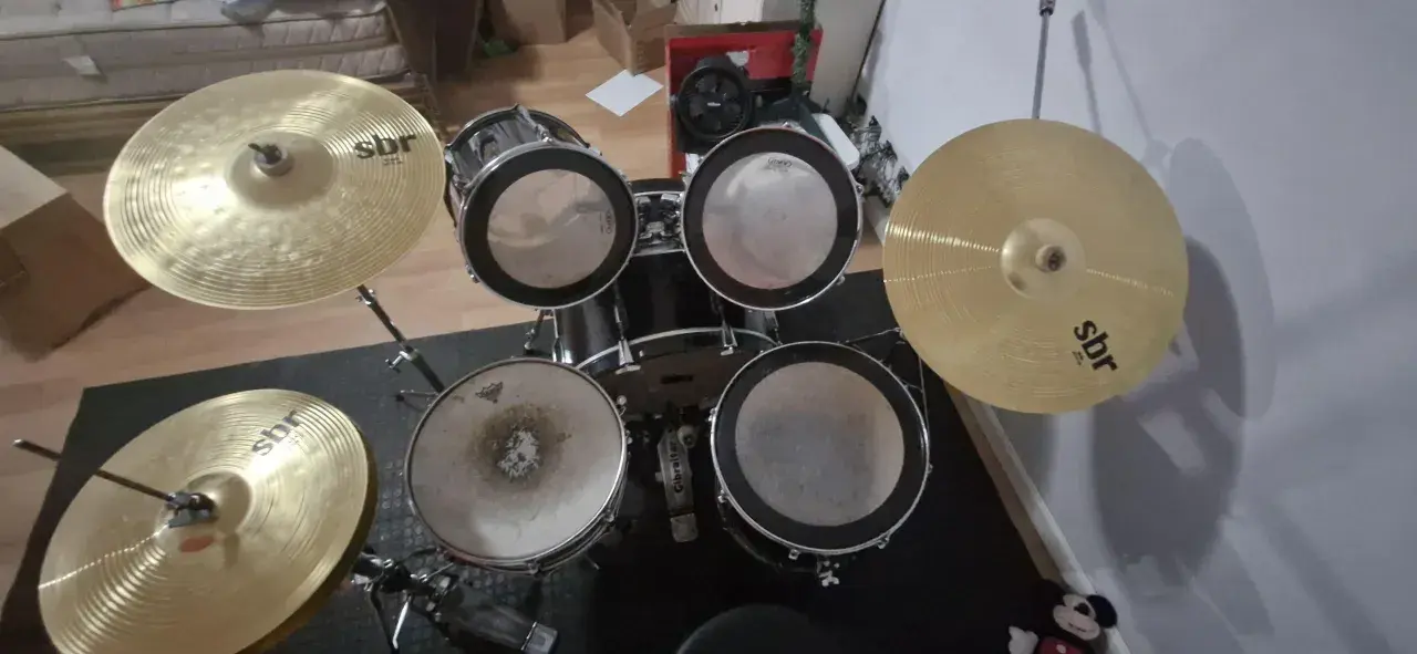 Un kit de batterie SBR avec cymbales brillantes, prêt pour que Tom aiguille les rythmes.