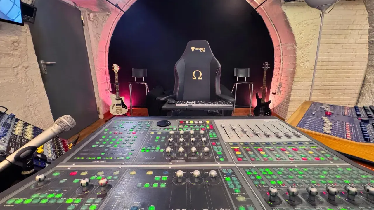 Console de mixage analogique dans un studio d'enregistrement, avec guitares et fauteuil de gamer.