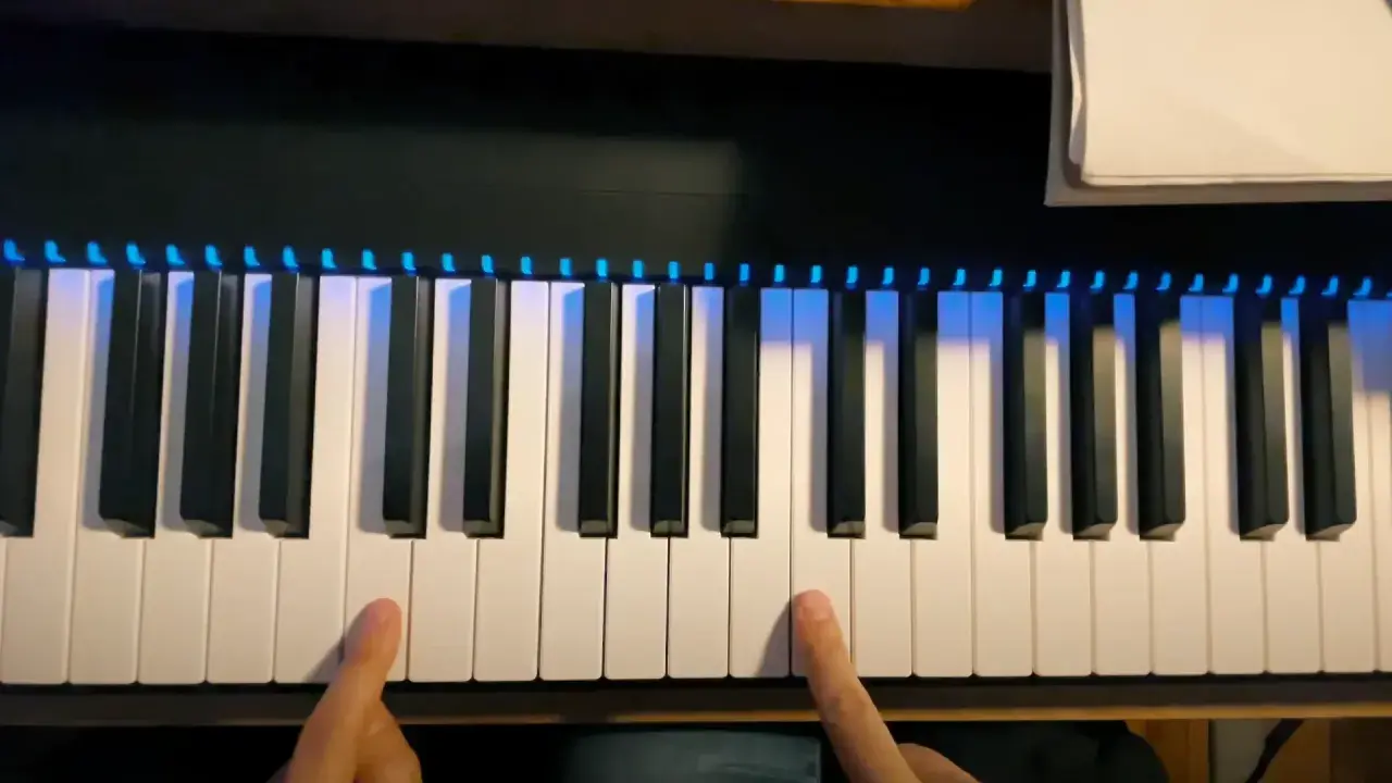 Les doigts prêts à jouer des notes sur un clavier de piano illuminé.