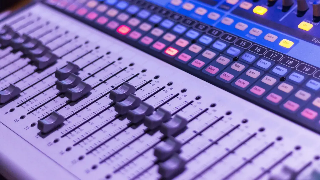 Console de mixage avec des curseurs et des boutons lumineux, prête pour une session d'enregistrement.