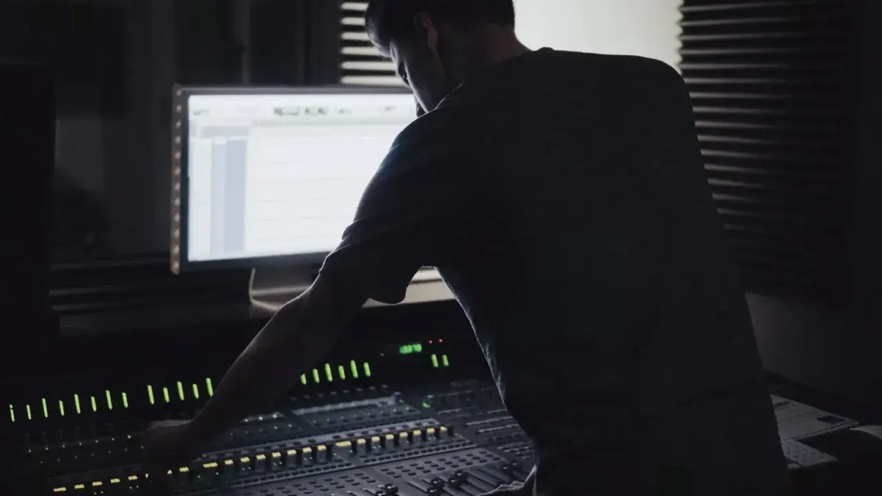 Un ingénieur du son ajuste la console, créant un mixage audio de qualité mp3 320 kbps.