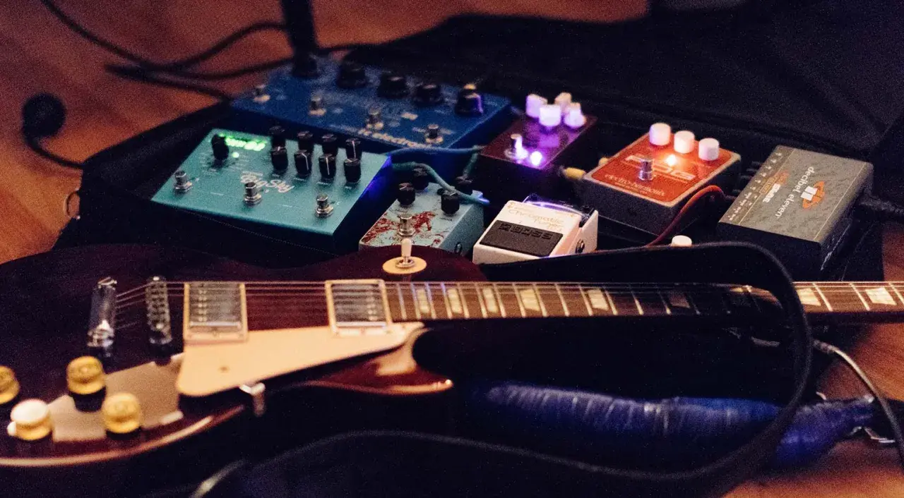 Guitare électrique et pédales d'effets, dont un sustainer guitare, prêtes pour la scène.