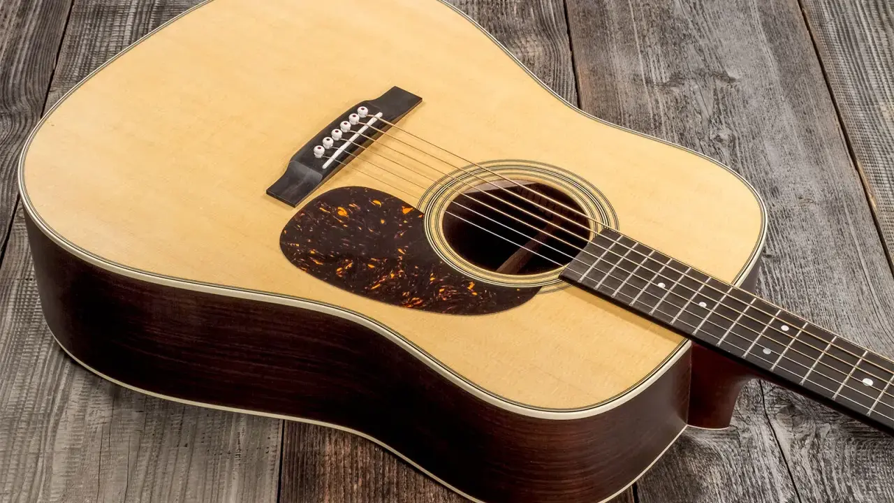 Une guitare acoustique Martin D-28, avec son corps en bois sombre et sa table claire, repose sur un fond de planches de bois grises.