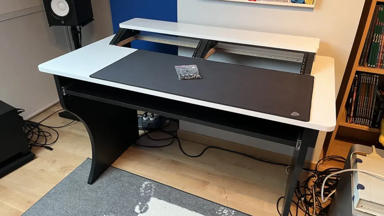 Bureau d'angle noir et blanc, prêt pour faire de la musique sur PC. Haut-parleur, tapis de souris et étagères pour équipement audio.