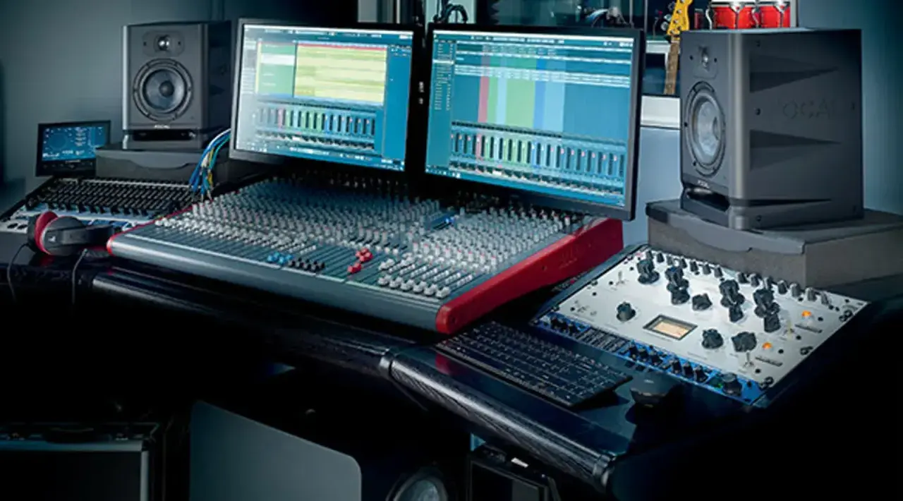 Studio d'enregistrement avec deux écrans affichant des pistes audio, une console de mixage, des enceintes Focal et du matériel pour cree une prod.