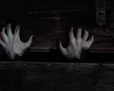 Mains pâles aux doigts noircis sortant d'une caisse en bois sombre, évoquant une musique qui fait peur au piano.