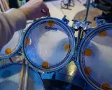 Main d'un batteur ajustant un timbre sur une peau de batterie Evans, prêt à monter une batterie pour un concert.
