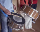 Des musiciens jouent de la percussion brésilienne, leurs mains tenant des baguettes prêtes à frapper les tambours.