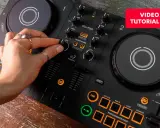 Main d'une personne manipulant une table de mixage pour créer sa propre musique électro. Tutoriel vidéo disponible.
