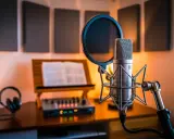 Studio d'enregistrement avec un micro line, un pupitre, des écouteurs et une console de mixage.