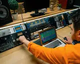 Un ingénieur du son ajuste les réglages sur une console audio, maîtrisant son studio pour un mixage parfait.