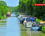 Bateaux amarrés sur le Canal du Midi, bordé d'arbres verdoyants. Un voyage paisible sur les eaux calmes.