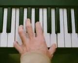 Main d'un pianiste sur des touches noires et blanches, symbolisant le passage de l'analogique au numérique.