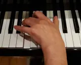 Main droite jouant un accord de ré mineur sur un piano.