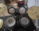 Un kit de batterie SBR avec cymbales brillantes, prêt pour que Tom aiguille les rythmes.