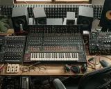 Studio d'enregistrement avec table de mixage, synthétiseurs et enceintes. Un espace dédié au mix audio, prêt à créer des sons uniques.