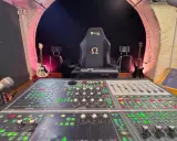 Console de mixage analogique dans un studio d'enregistrement, avec guitares et fauteuil de gamer.