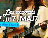 Une musicienne joue de la guitare, expliquant les accords 7, m7, MAJ7.
