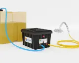 Système Solaris : un réservoir jaune alimente un boîtier noir par un tuyau bleu. Un tuyau jaune sort du boîtier, projetant de l'eau.