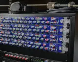 Rack de matériel audio avec plusieurs modules SSL Super 9000, un microphone et un casque.