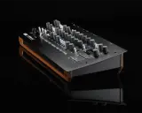 Synthétiseur Korg minilogue xd noir avec finitions bois, posé sur une surface réfléchissante.