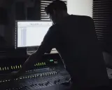 Un ingénieur du son ajuste la console, créant un mixage audio de qualité mp3 320 kbps.