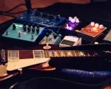 Guitare électrique et pédales d'effets, dont un sustainer guitare, prêtes pour la scène.