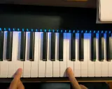 Deux doigts prêts à jouer un accord sur un piano numérique avec des lumières bleues illuminant les touches.