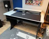 Bureau d'angle noir et blanc, prêt pour faire de la musique sur PC. Haut-parleur, tapis de souris et étagères pour équipement audio.