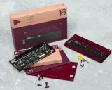 Le **pocket operator** modular 16, son circuit imprimé et sa boîte sur fond gris. Un appareil pour créer de la musique.