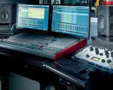 Studio d'enregistrement avec deux écrans affichant des pistes audio, une console de mixage, des enceintes Focal et du matériel pour cree une prod.