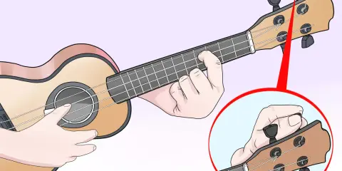 Main gauche sur le manche, main droite sur la tête pour accorder l'ukulele. Gros plan sur le réglage d'une corde.