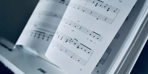 Partition piano triste ouverte sur un piano. Les notes semblent raconter une histoire mélancolique.