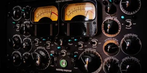 Panneau de compresseur mastering avec deux VU-mètres lumineux. Apprenez comment utiliser un compresseur en ajustant les nombreux boutons et sélecteurs.