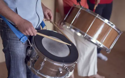 Des musiciens jouent de la percussion brésilienne, leurs mains tenant des baguettes prêtes à frapper les tambours.