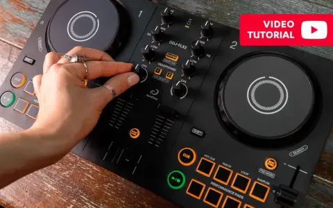 Main d'une personne manipulant une table de mixage pour créer sa propre musique électro. Tutoriel vidéo disponible.