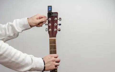 Main tenant de la guitare, il utilise un accordeur pour accorder l'instrument.