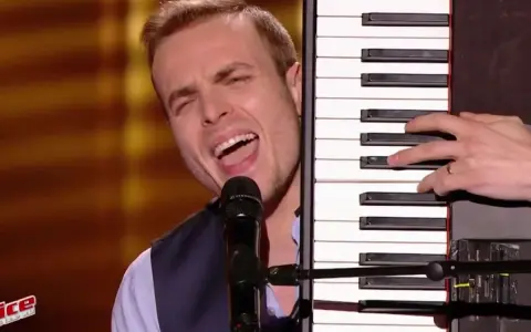 Un chanteur interprète une musique à faire au piano, sa voix résonne dans la salle.