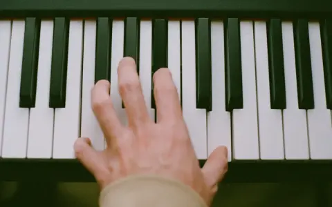 Main d'un pianiste sur des touches noires et blanches, symbolisant le passage de l'analogique au numérique.