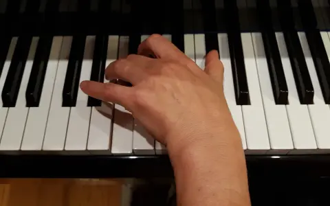 Main droite jouant un accord de ré mineur sur un piano.