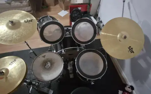 Un kit de batterie SBR avec cymbales brillantes, prêt pour que Tom aiguille les rythmes.