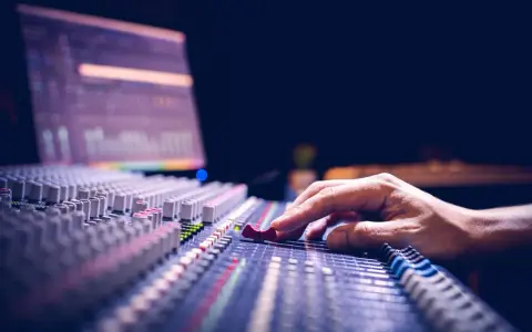 Main d'un ingénieur du son ajustant les curseurs d'une console de mixage pour optimiser la phase audio.
