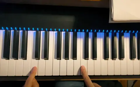 Les doigts prêts à jouer des notes sur un clavier de piano illuminé.
