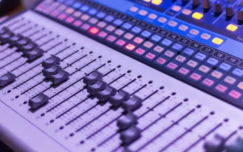 Console de mixage avec des curseurs et des boutons lumineux, prête pour une session d'enregistrement.