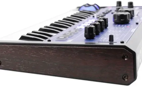 Clavier synthétiseur mini nova avec finitions bois sombre et panneau bleu lumineux.