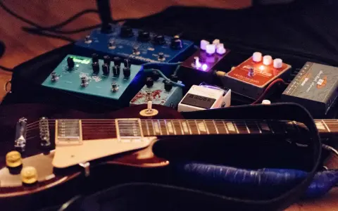 Guitare électrique et pédales d'effets, dont un sustainer guitare, prêtes pour la scène.